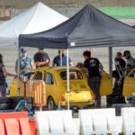 Tom Cruisestood next to a vintage yellow care in his grey suit and shirt for Mission: Impossible 7 in Rome, Italy