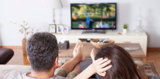 What Should Be the Difference Between Home TVs And Hotel TVs? young couple watching tv at living room